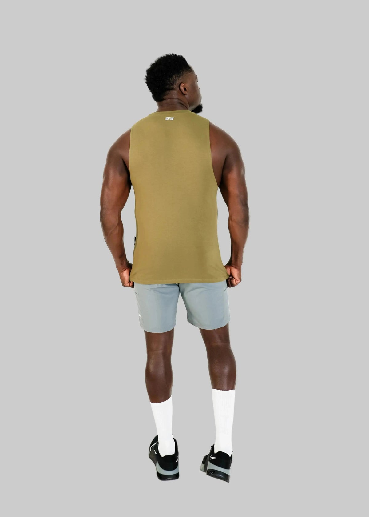 Person wearing a green tank top and light gray shorts on a white background