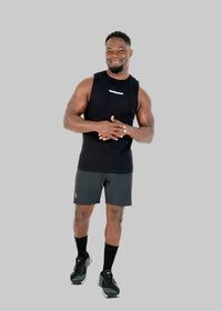 Man wearing a black sleeveless shirt and gray shorts on a white background