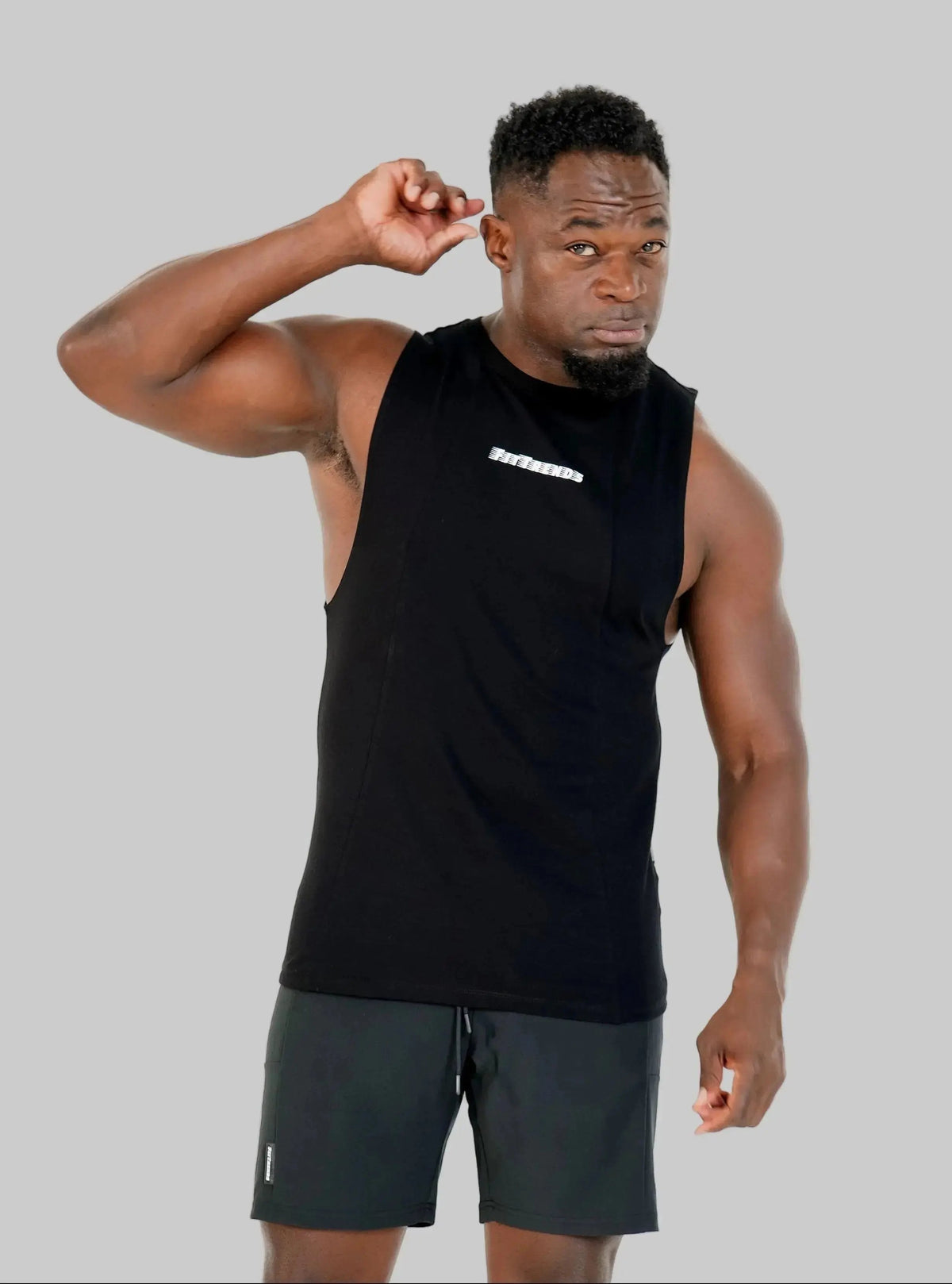Man wearing a black sleeveless shirt and gray shorts on a white background