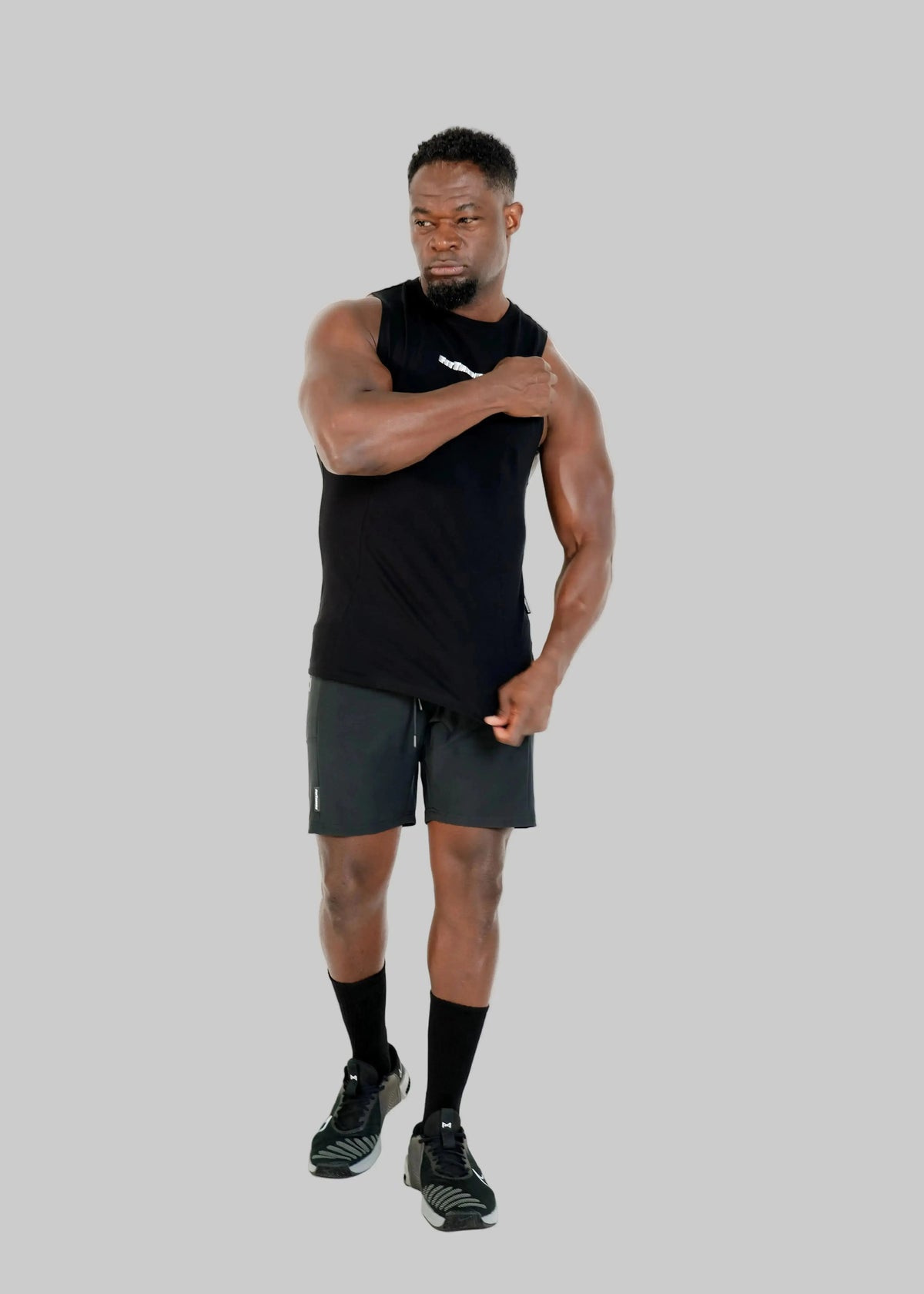 Man wearing a black sleeveless shirt and shorts on a white background