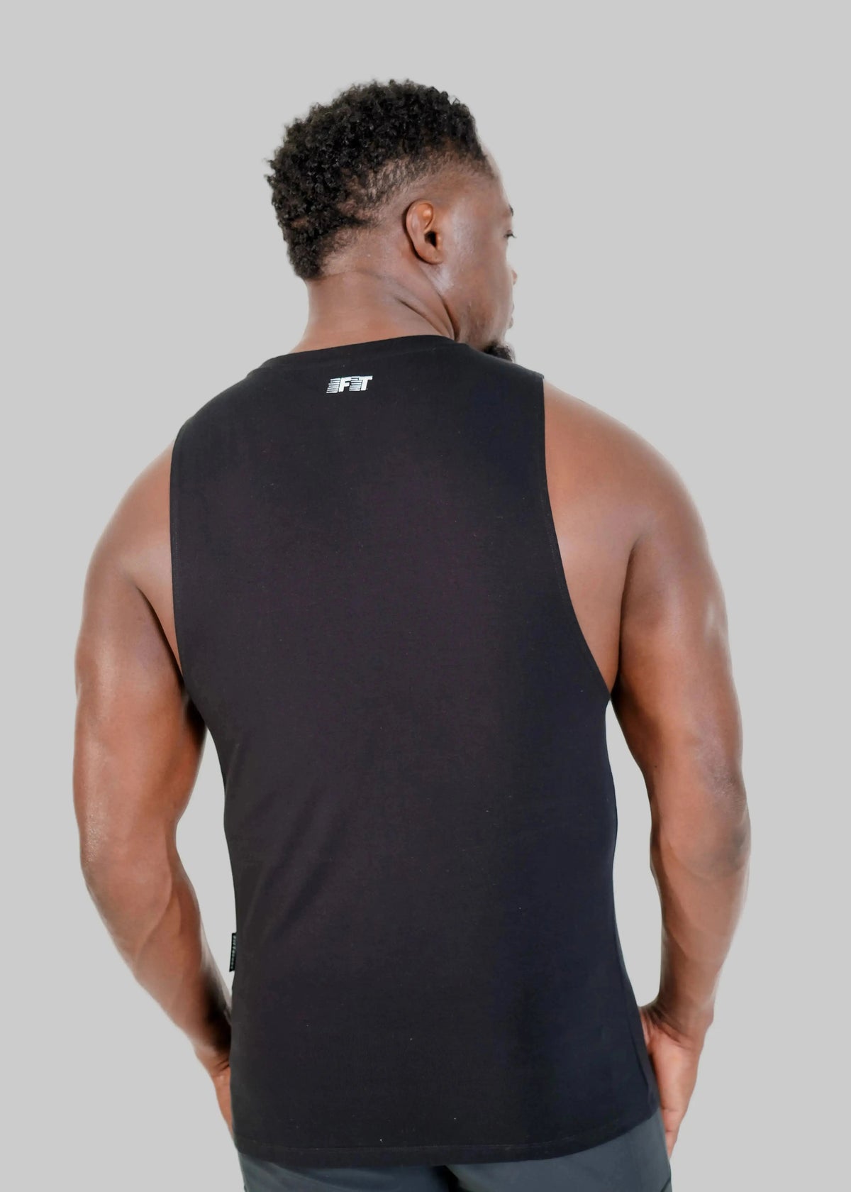Person wearing a black tank top with a logo on the back against a white background