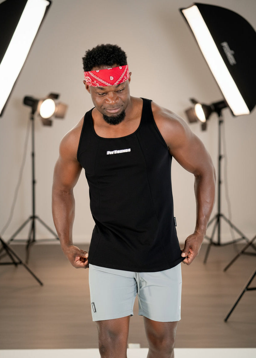 Man wearing a black tank top and gray shorts with a red bandana on a white background
