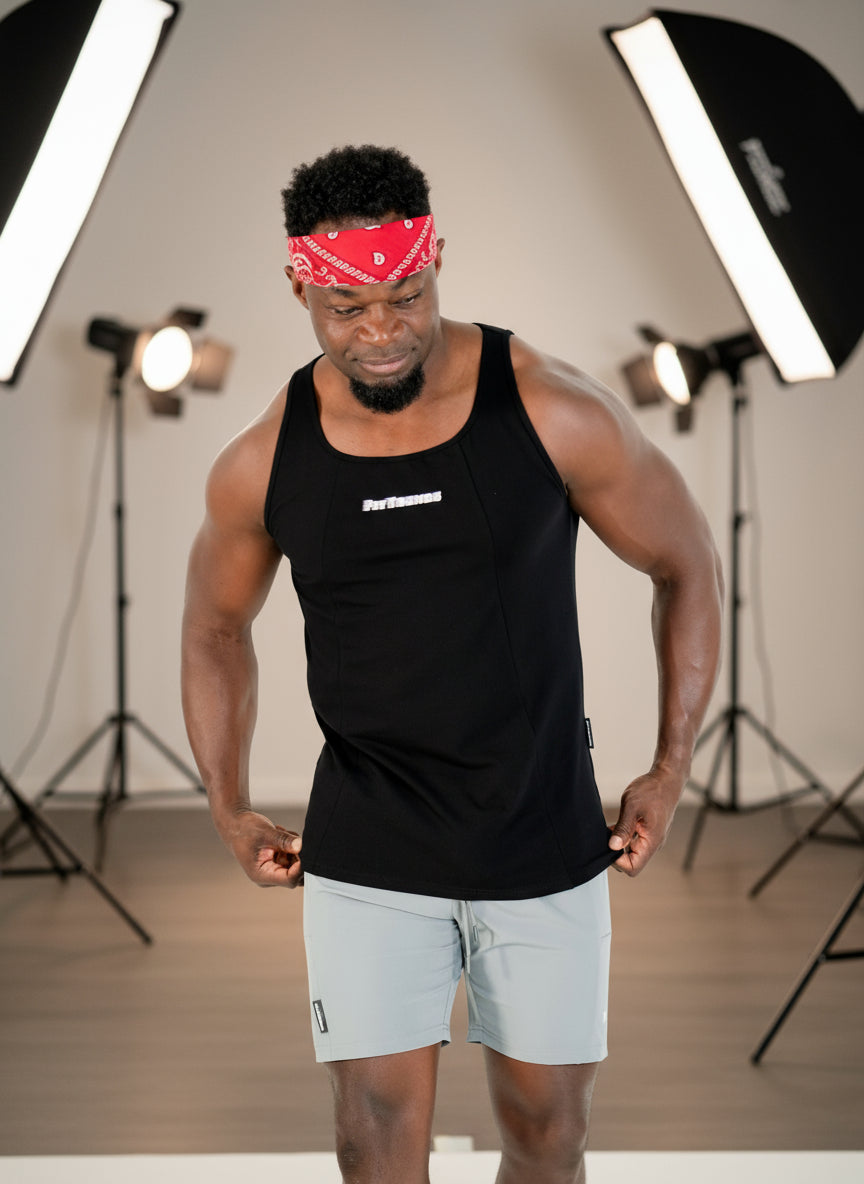 Man wearing a black tank top and gray shorts with a red bandana on a white background