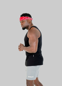 Man wearing a black tank top and gray shorts with a red bandana on a white background