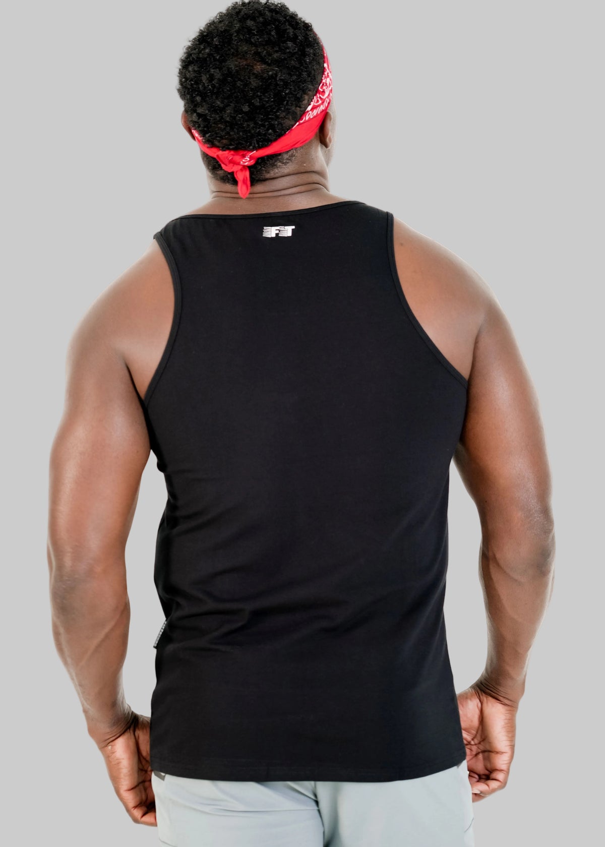 Person wearing a black tank top with a visible brand logo on the back, standing against a white background.