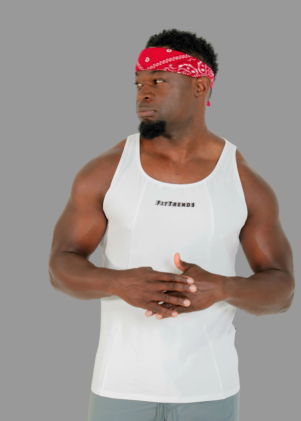 Man wearing a white tank top with text and a red bandana, standing against a plain background