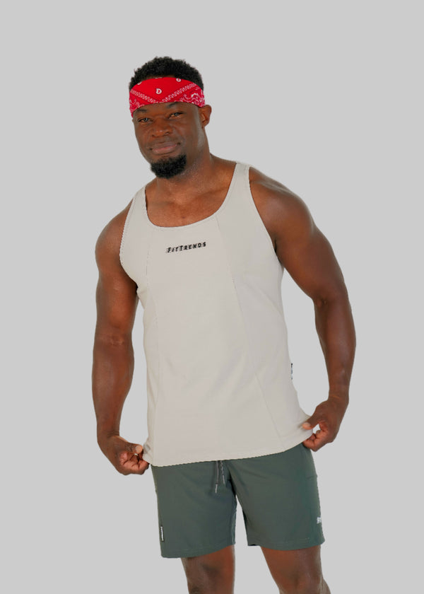 Man wearing a beige tank top and green shorts with a red bandana on a white background
