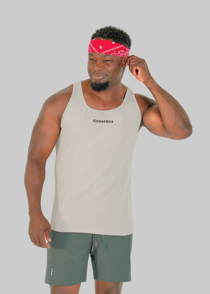 Man wearing a beige tank top and green shorts with a red bandana on a white background