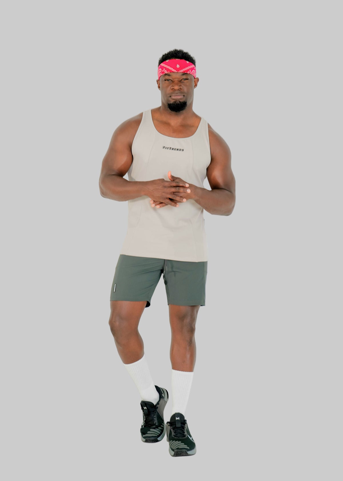 Man wearing a beige tank top and green shorts on a white background