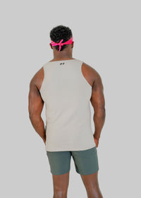 Person wearing a beige tank top and green shorts with a pink headband, standing against a white background
