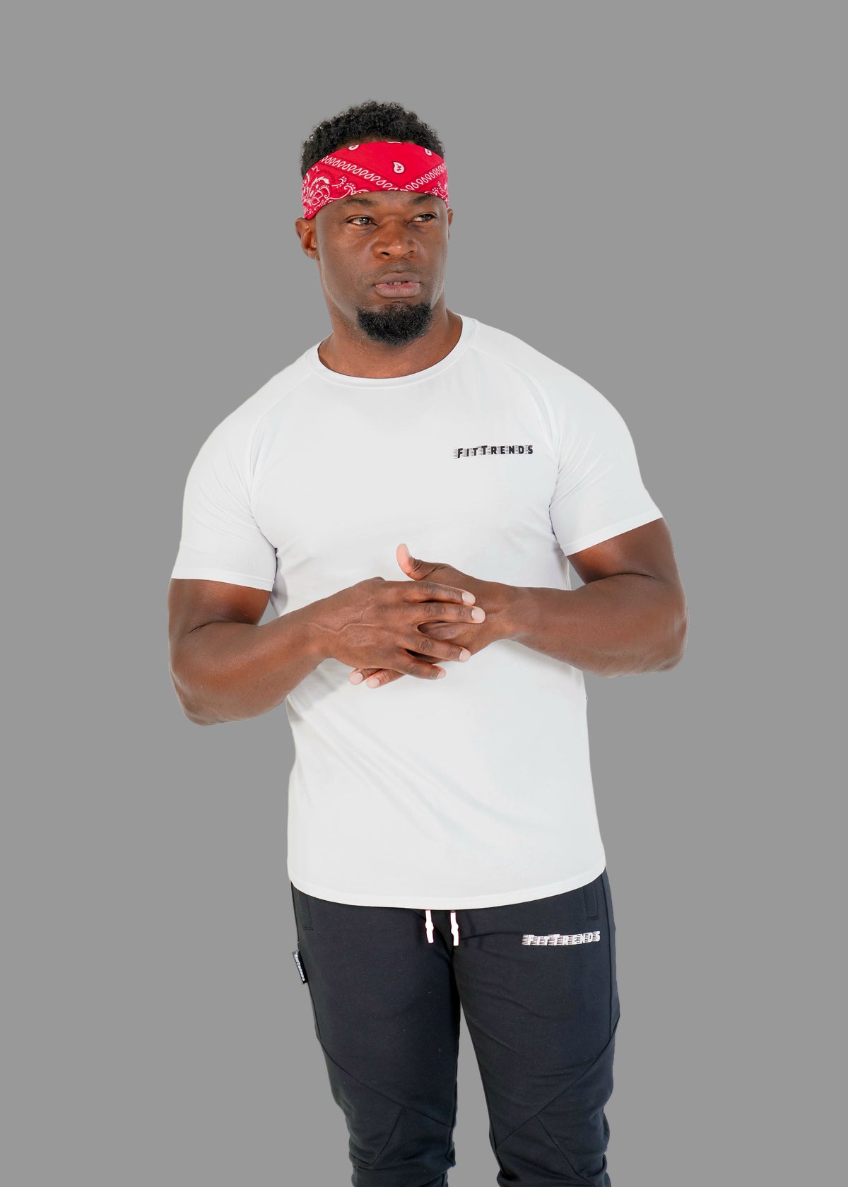 Man wearing a white t-shirt and black pants with visible branding, standing against a plain background.