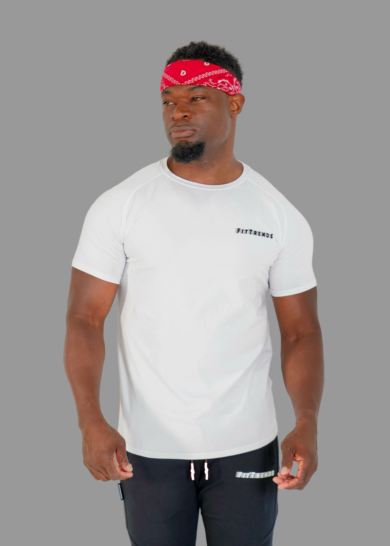 Man wearing a white t-shirt with text and dark pants on a plain background