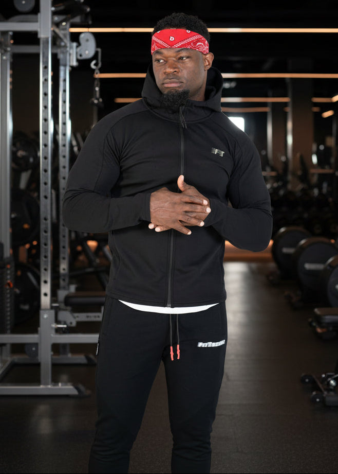 Man wearing a black hoodie and pants with a red bandana on a white background