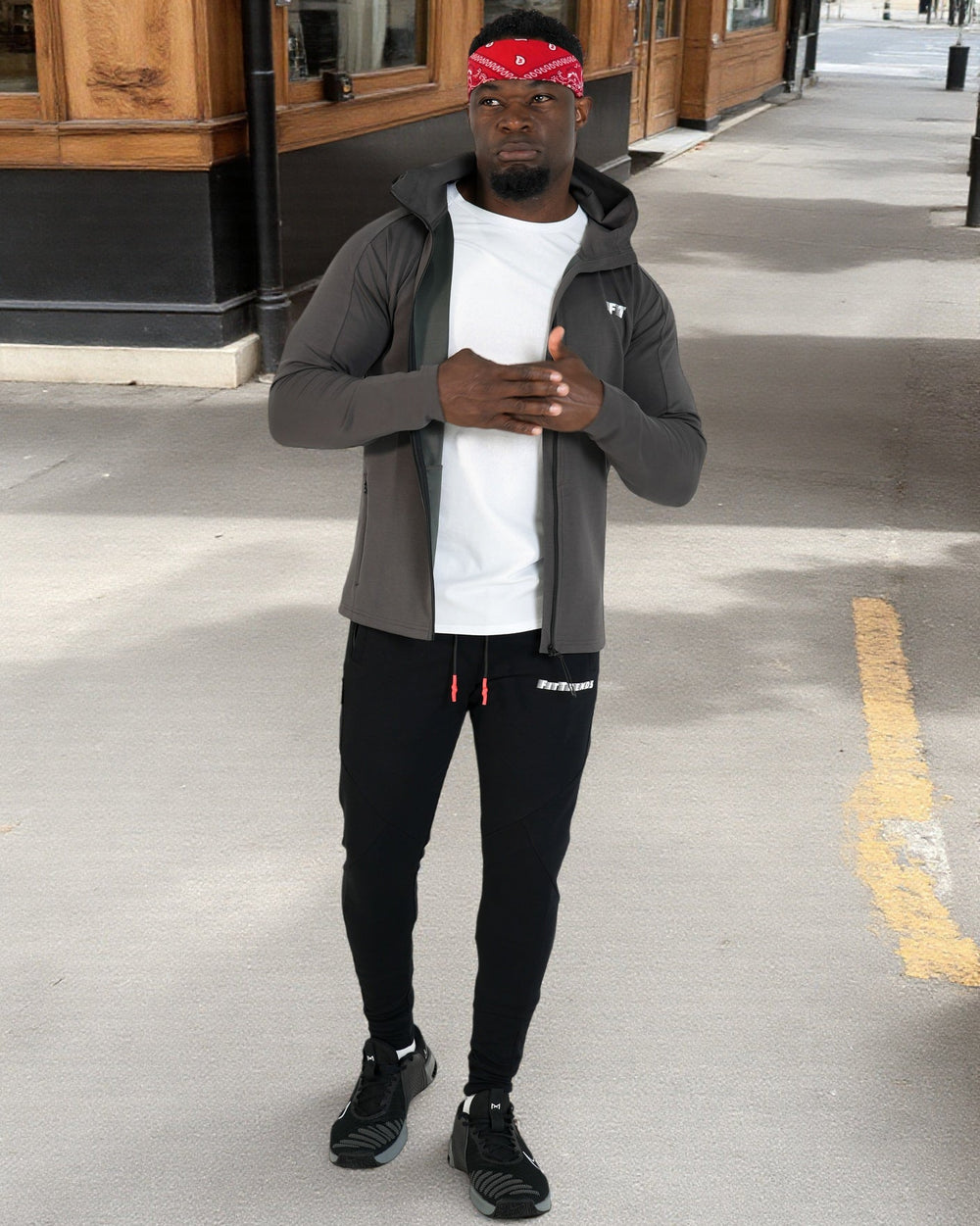 Person wearing a gray jacket, white shirt, black pants, and black shoes on a city street.