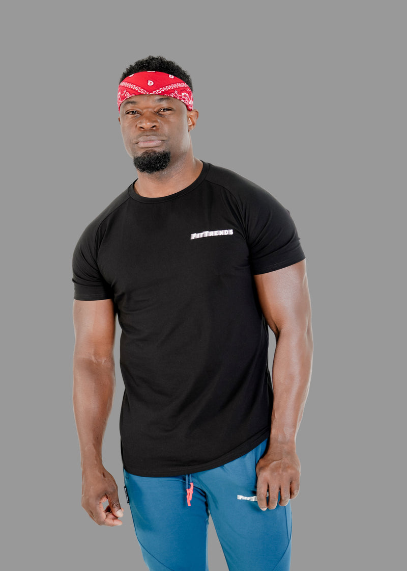 Man wearing a black t-shirt with a brand logo and blue pants on a white background