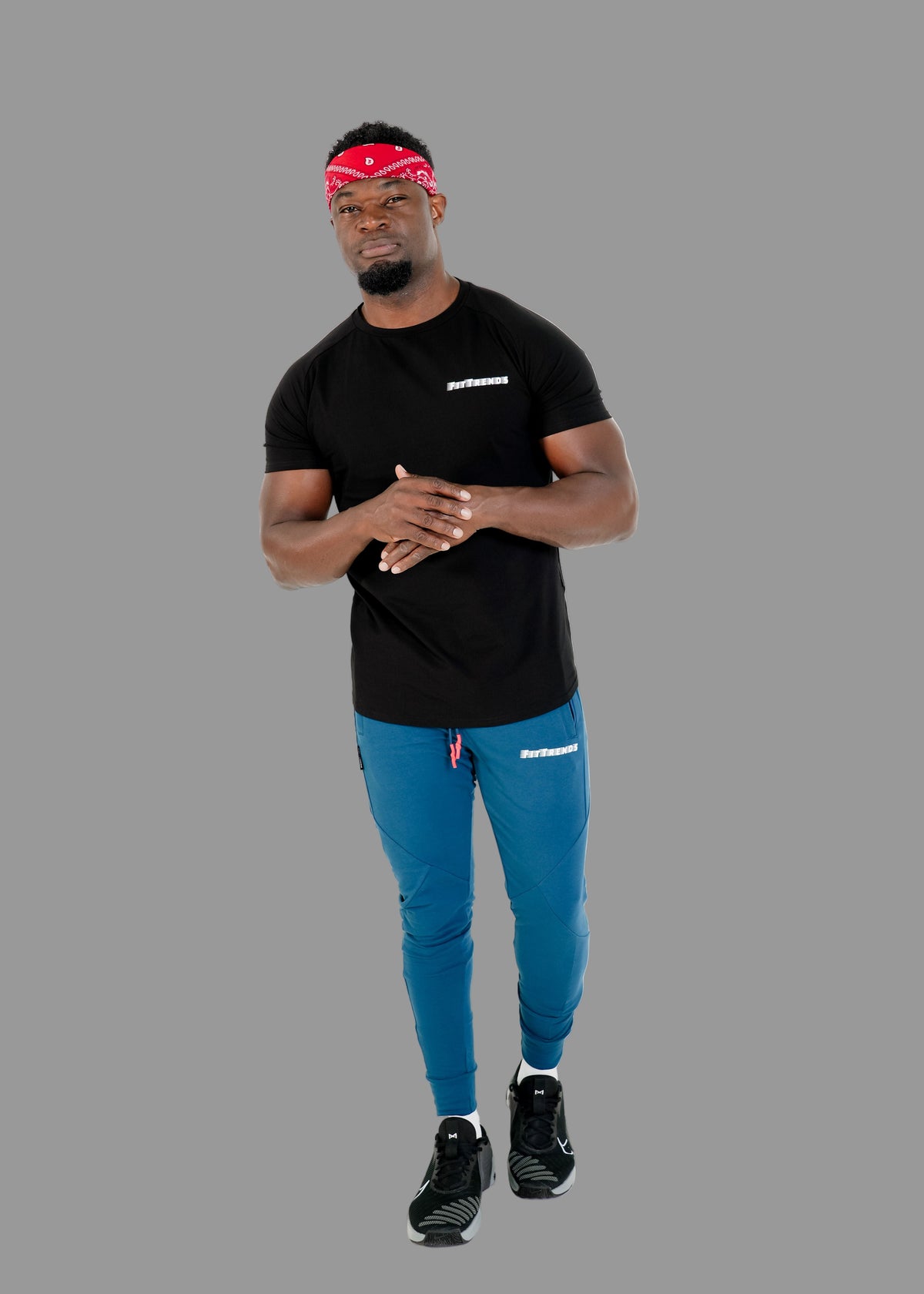 Man wearing a black t-shirt, blue pants, and a red headband with a brand logo on a white background