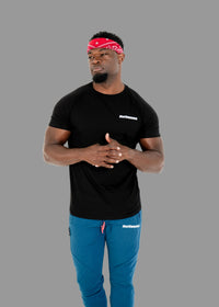 Man wearing a black t-shirt and blue pants with a red bandana, standing against a white background.