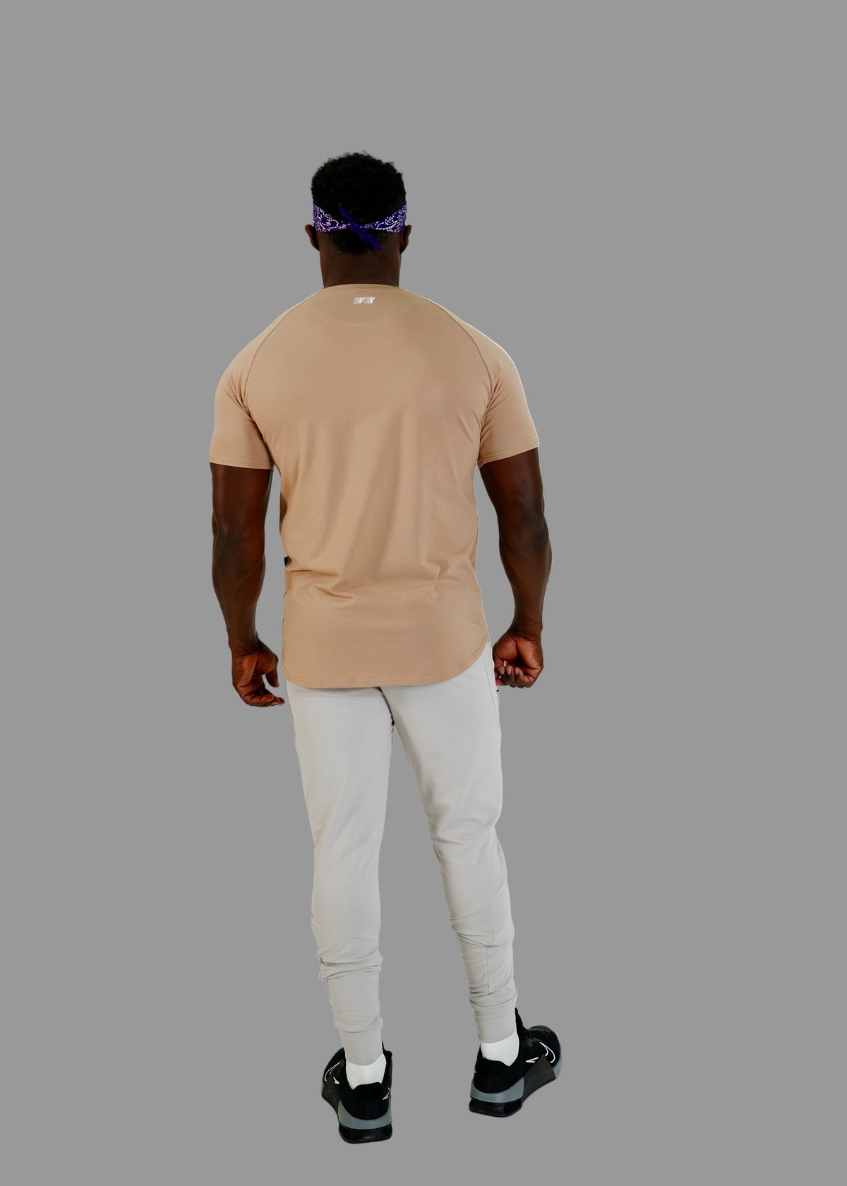 Person wearing a beige t-shirt and light gray pants on a white background