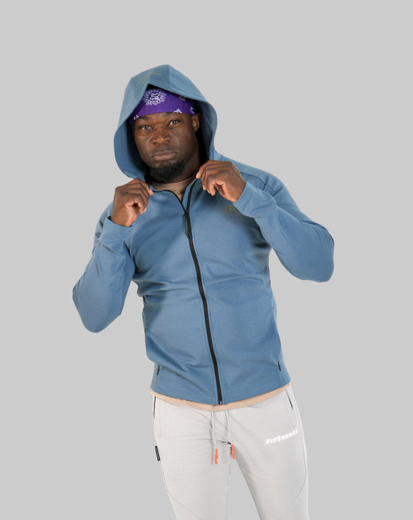 Person wearing a blue hoodie and white pants on a white background