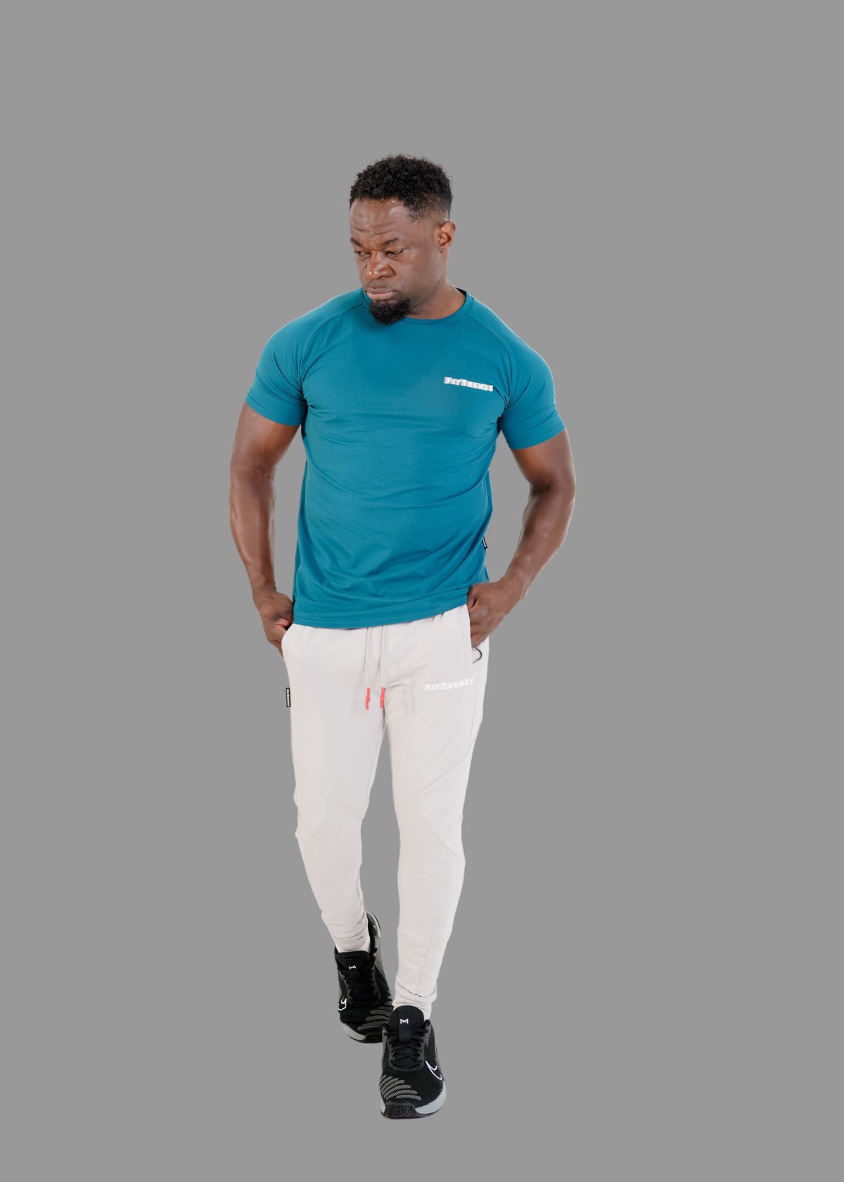 Man wearing a teal t-shirt and white pants on a white background