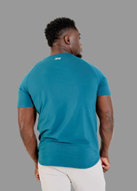 Man wearing a teal t-shirt with a logo on the back against a white background