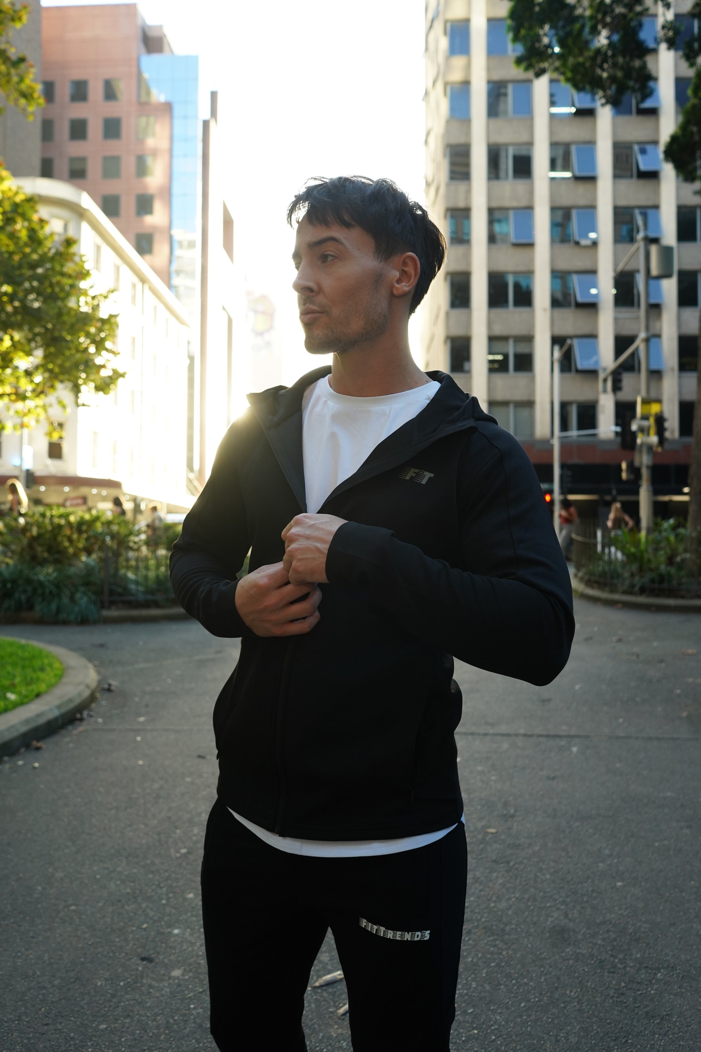 Person in a black suit standing on a city street with buildings in the background