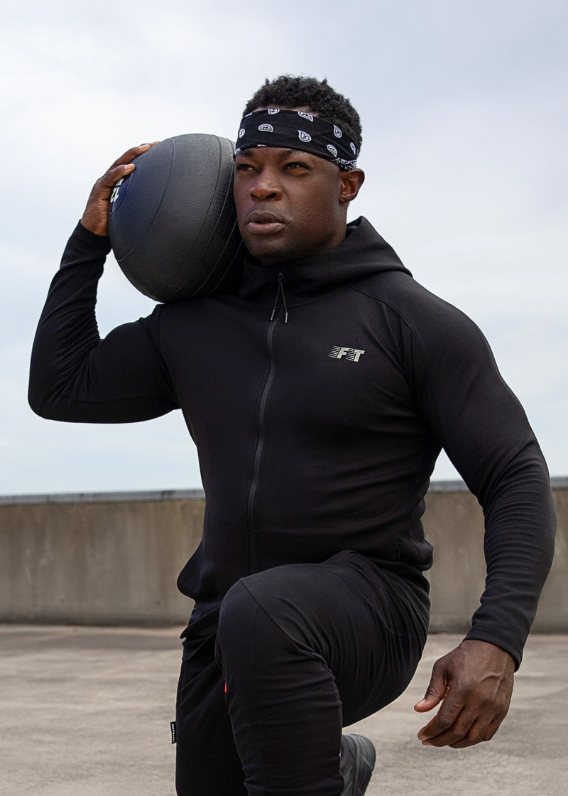 Person in black athletic wear holding a medicine ball on a rooftop.