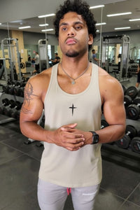 Man in a gym wearing a tank top and light pants