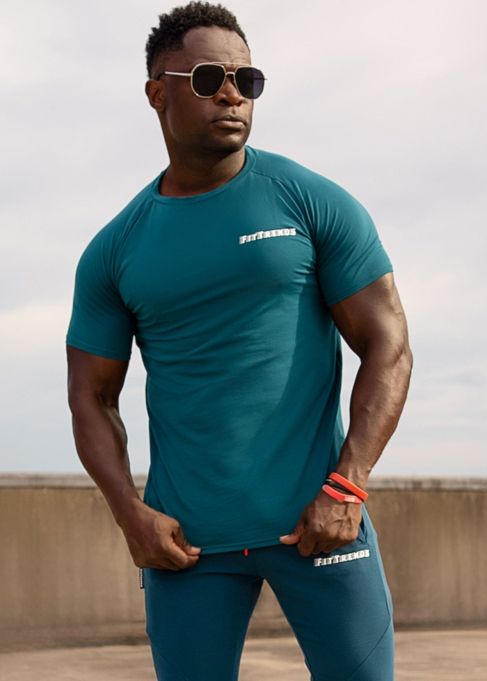 Man wearing a teal athletic outfit with visible branding against a neutral background