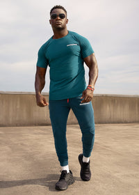 Man wearing a teal athletic outfit with sunglasses on a rooftop.