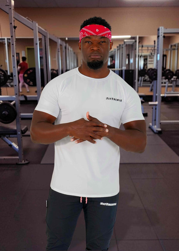 Man in a gym wearing a white t-shirt and black pants with a red bandana.