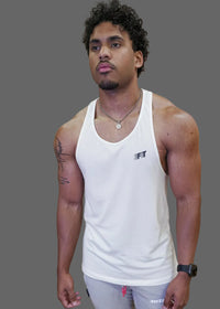 Man wearing a white tank top with a brand logo in front of a wooden wall with pink text.