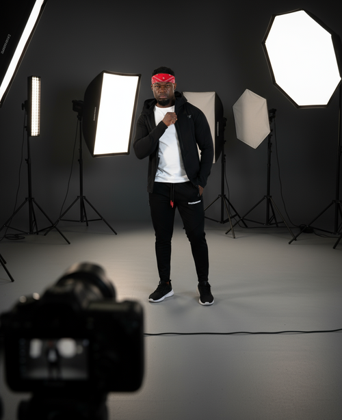 Person in a studio with photography equipment, including lights and camera.