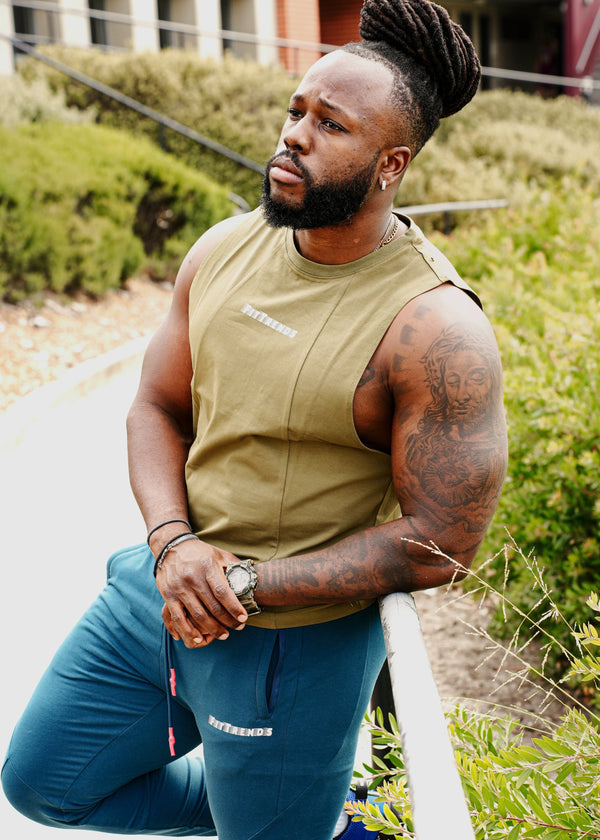 Man in athletic wear standing outdoors with greenery and a building in the background