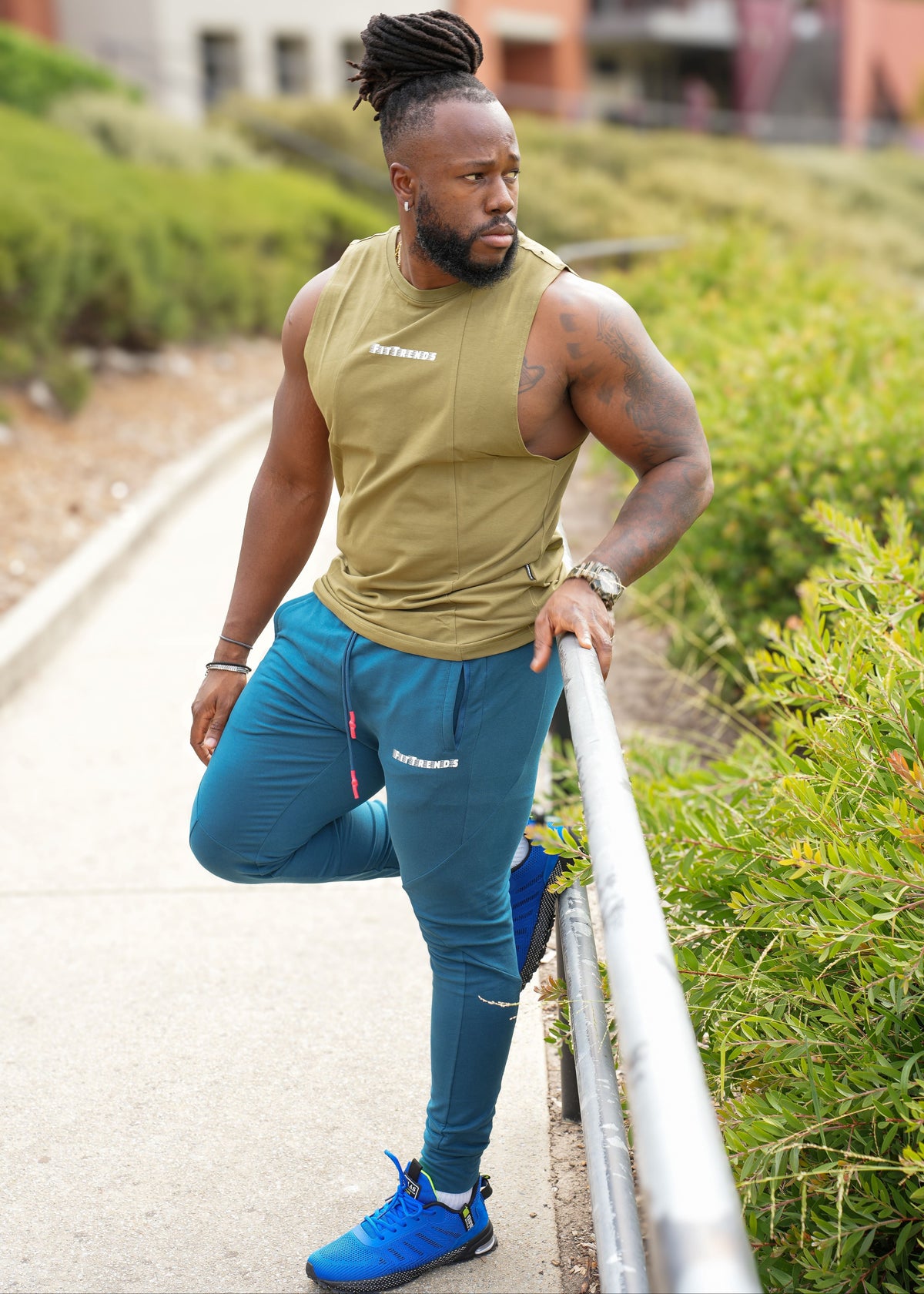 Man in athletic wear standing outdoors on a path with greenery.