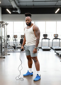 Man in athletic wear with jump rope on grassy field