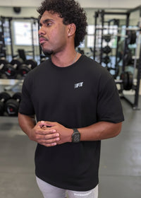 Man wearing a black t-shirt with a logo in a gym setting