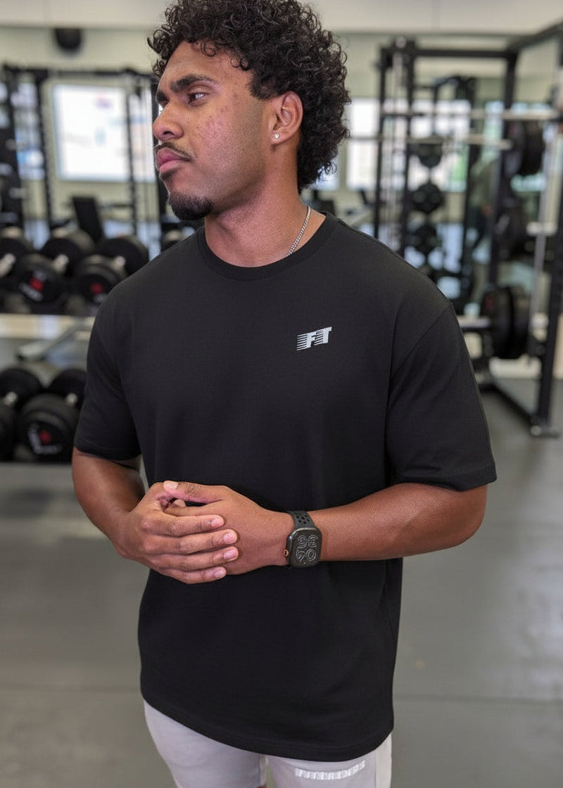 Man wearing a black t-shirt with a logo in a gym setting